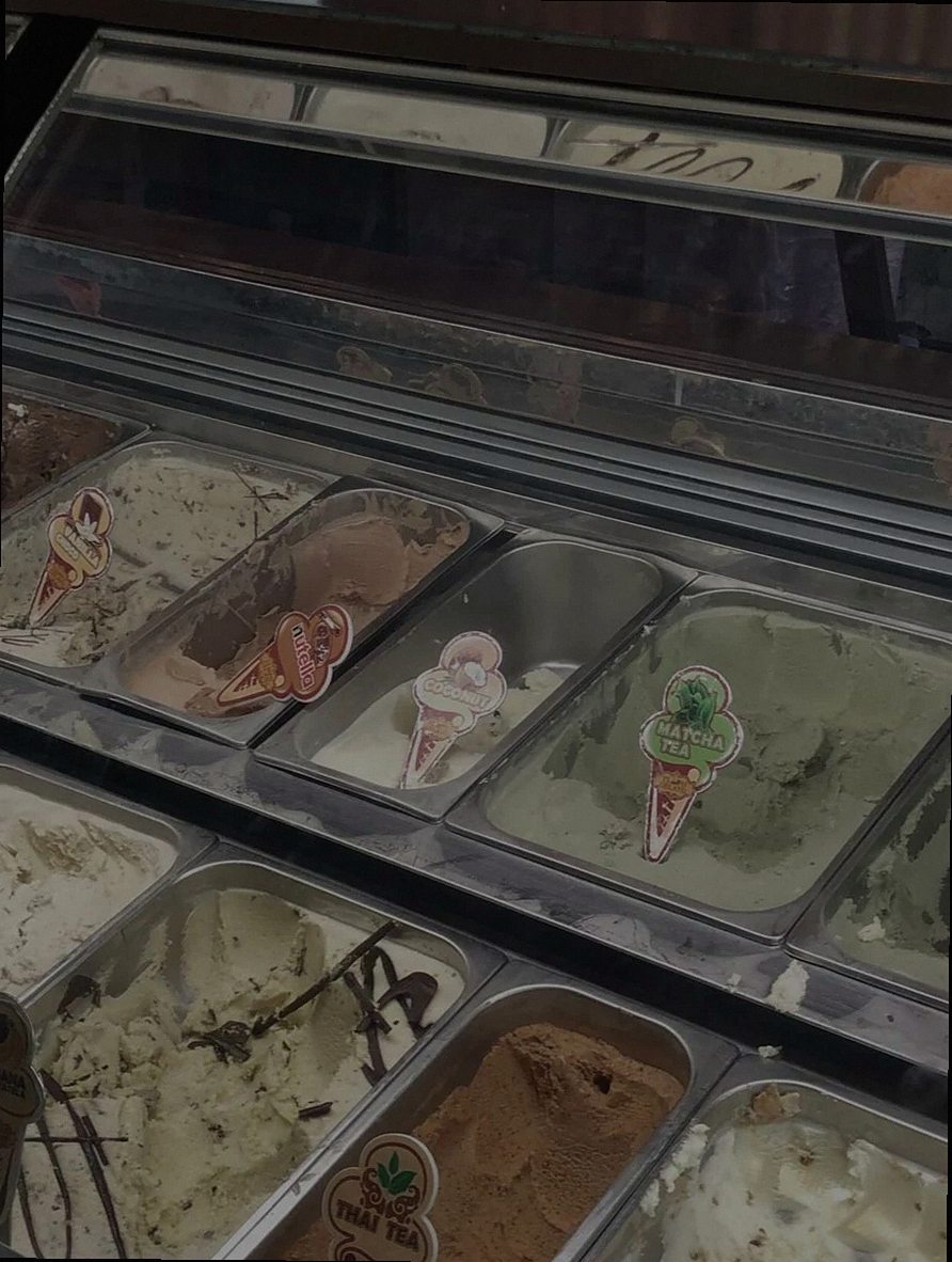 Una toma de cerca de varios sabores de helado en una vitrina congeladora, perfecta para fotografía gastronómica.