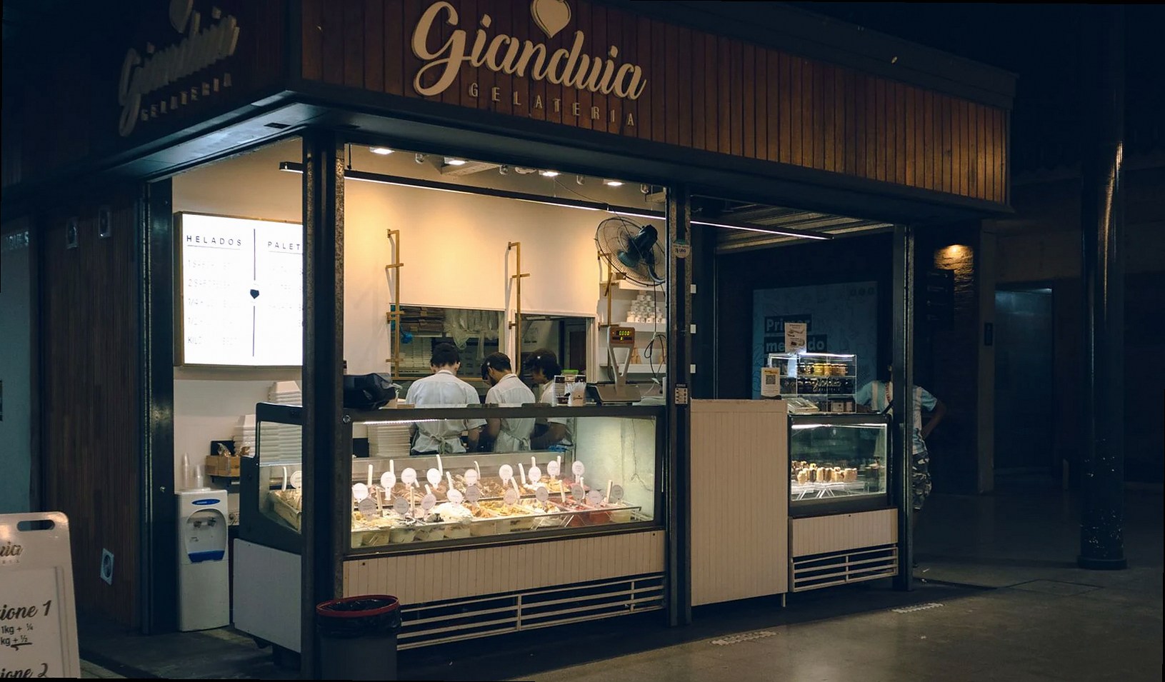 Vista nocturna de una heladería en Rosario, Argentina, con una vibrante iluminación interior.
